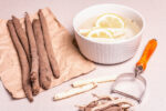 Raw Scorzonera or Spanish salsify. Process for cooking. Peel skin, and place in cold water with lemon. Modern vegetables, healthy food, suitable for diabetics. Stone background, copy space