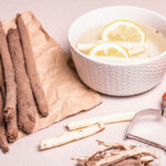 Raw Scorzonera or Spanish salsify. Process for cooking. Peel skin, and place in cold water with lemon. Modern vegetables, healthy food, suitable for diabetics. Stone background, copy space